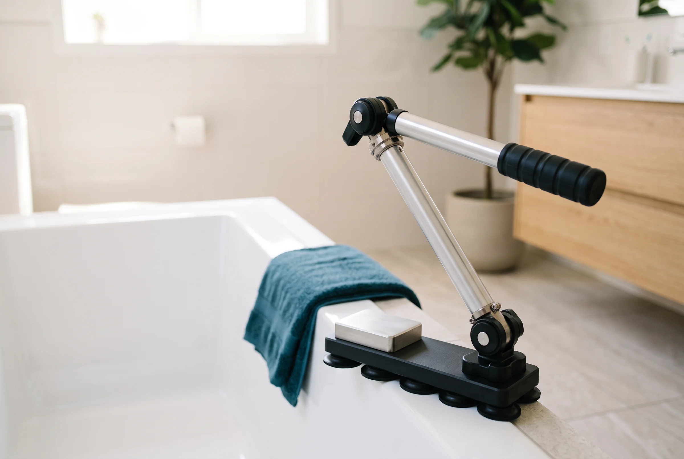 A bath support standing on the ledge of a white bathtub in a bright bathroom.